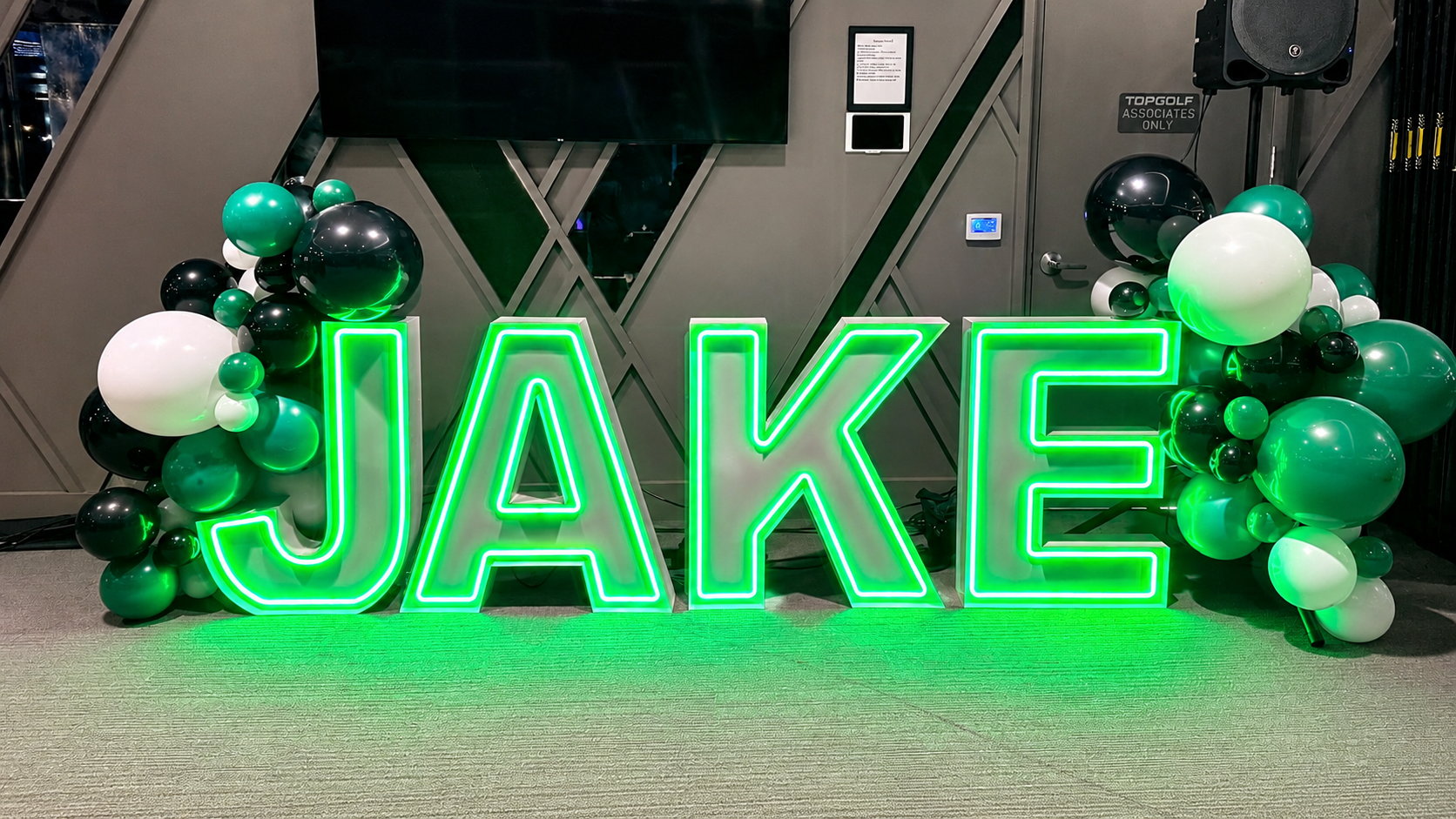 Green LED marquee letters spelling JAKE at a birthday