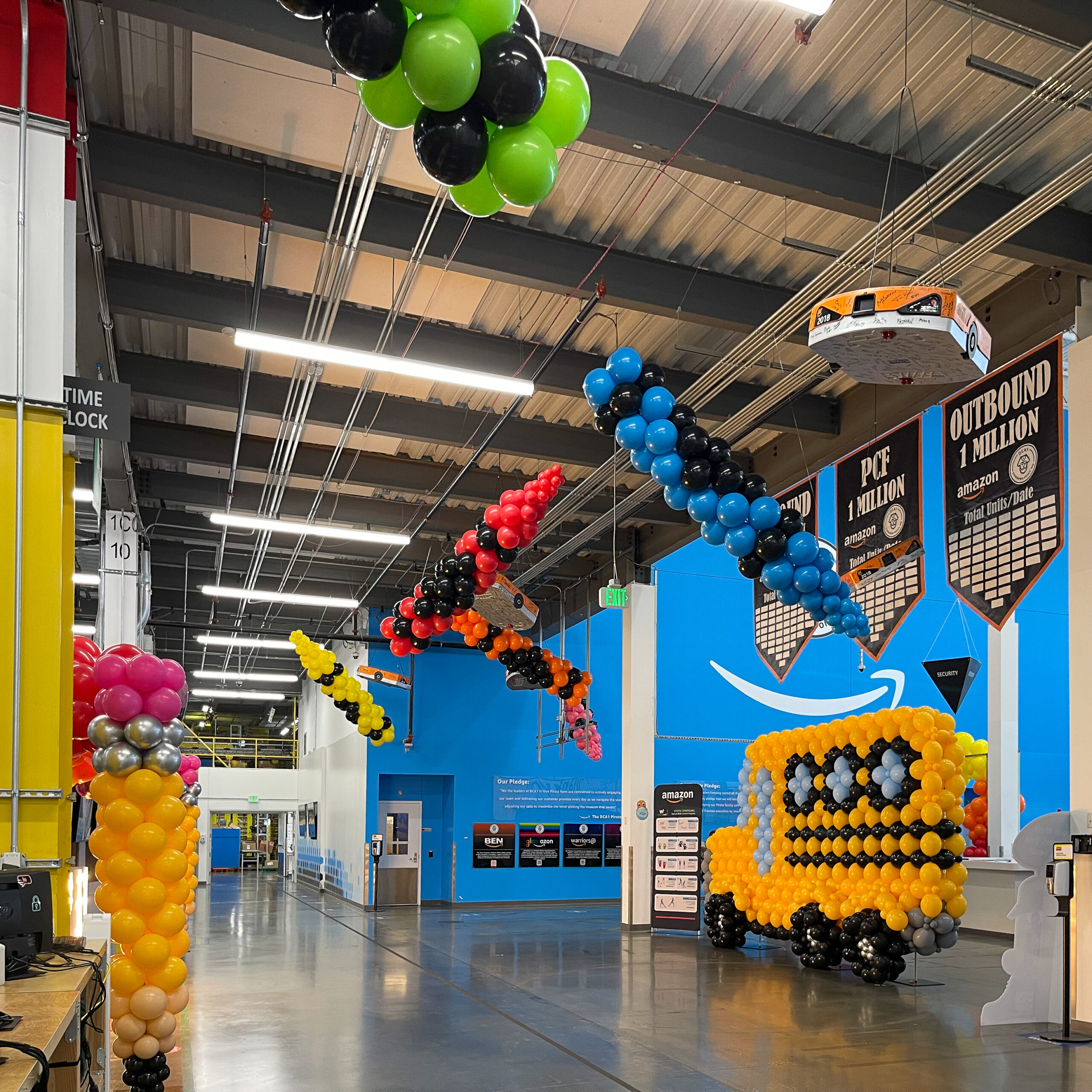 Balloon school bus sculpture and hanging ceiling installations at an Amazon warehouse