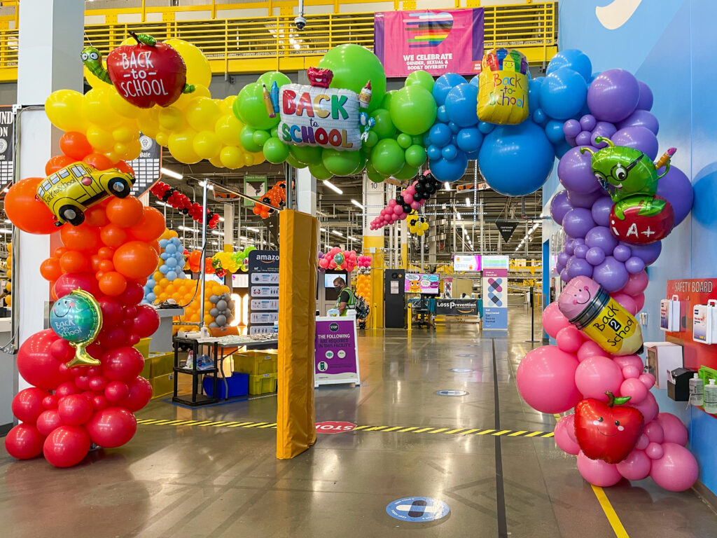Rainbow back-to-school balloon arch framing the entrance at an Amazon fulfillment center in Maryland