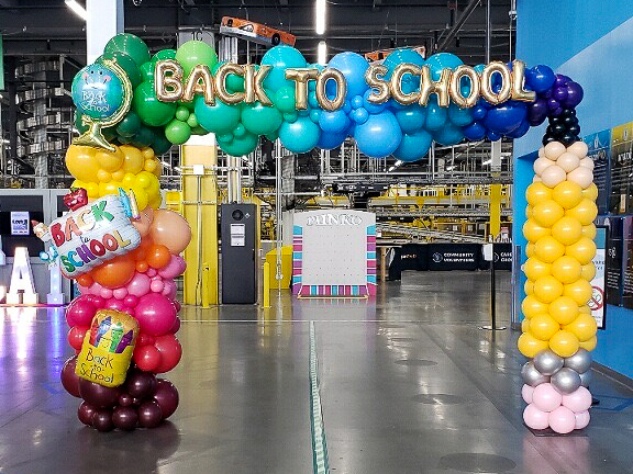 Gold BACK TO SCHOOL balloon letter arch at an Amazon fulfillment center