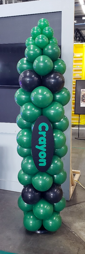 Green crayon-themed balloon column at an Amazon back-to-school event