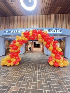 Organic red and gold balloon arch in a theatre